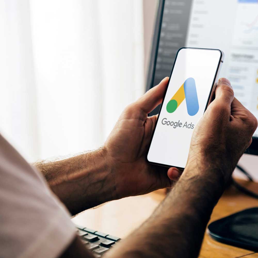 Person holding smartphone displaying Google Ads logo, emphasizing digital advertising services offered by Norra Sol.