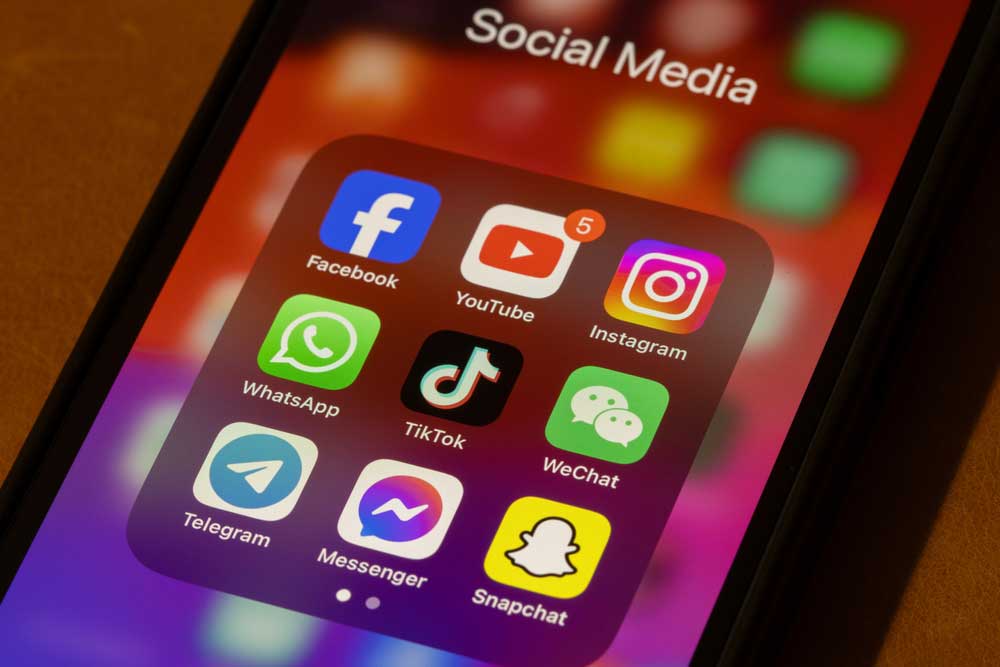 Social media icons on smartphone screen, including Facebook, YouTube, Instagram, TikTok, WhatsApp, WeChat, Telegram, Messenger, and Snapchat, representing digital engagement and social media management services.
